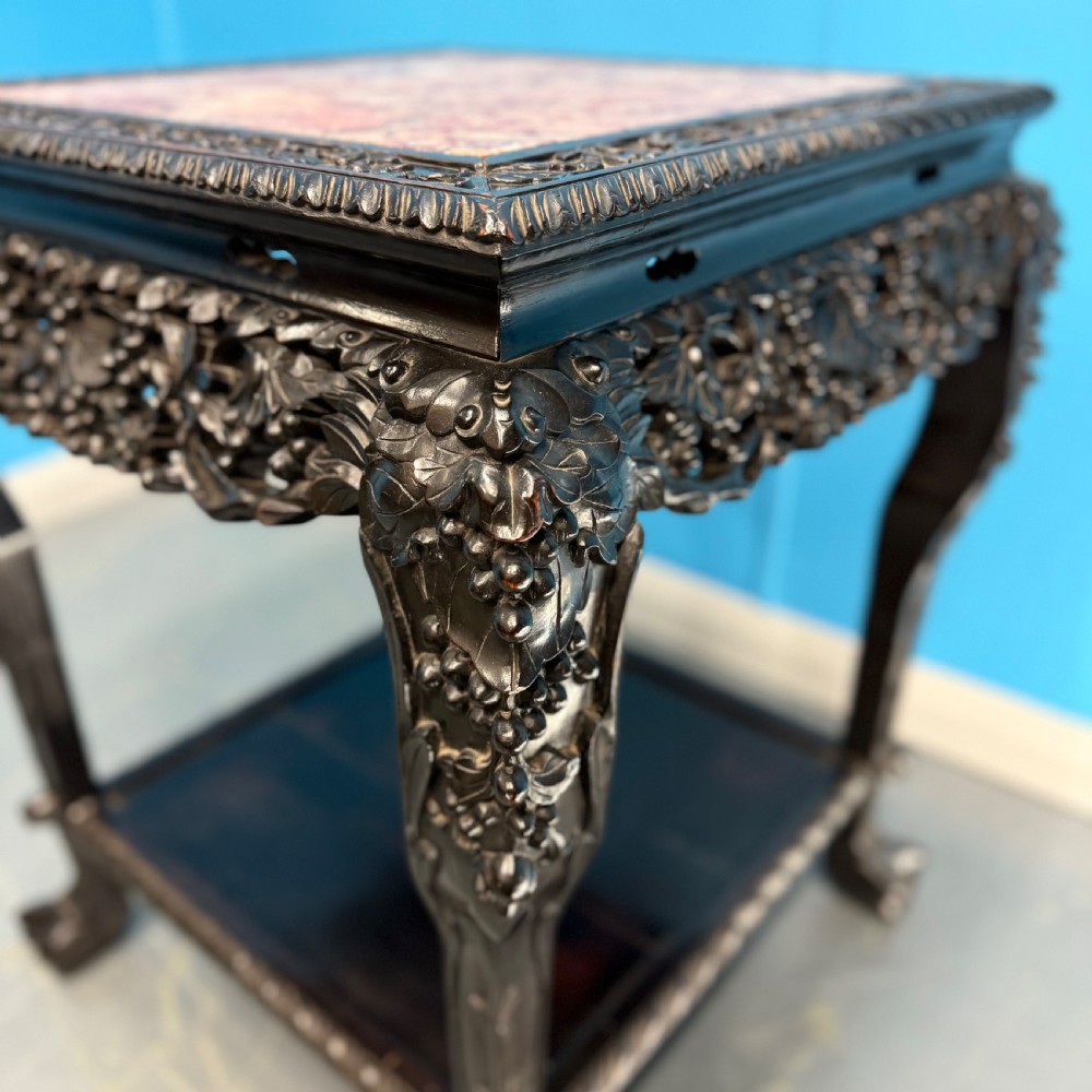 A dark carved Chinese hardwood side table with an inset pink marble top, openwork grapevine apron, cabriole legs, and a lower shelf. View V