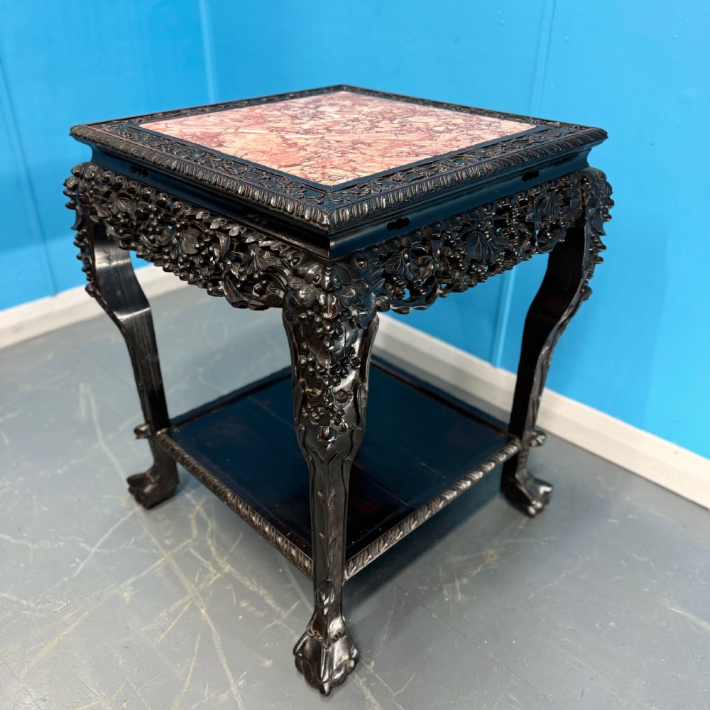 A dark carved Chinese hardwood side table with an inset pink marble top, openwork grapevine apron, cabriole legs, and a lower shelf. View VI