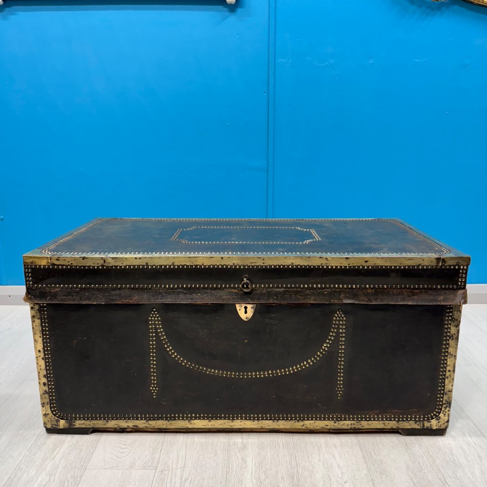 A 19th-century dark leather storage trunk featuring brass studding in geometric patterns, corner brackets, and drop handles. View III