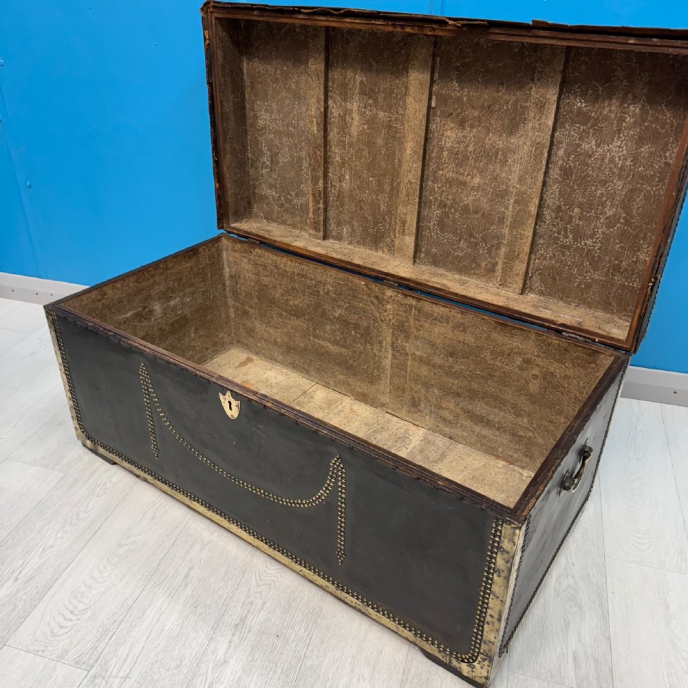 A 19th-century dark leather storage trunk featuring brass studding in geometric patterns, corner brackets, and drop handles. View VII