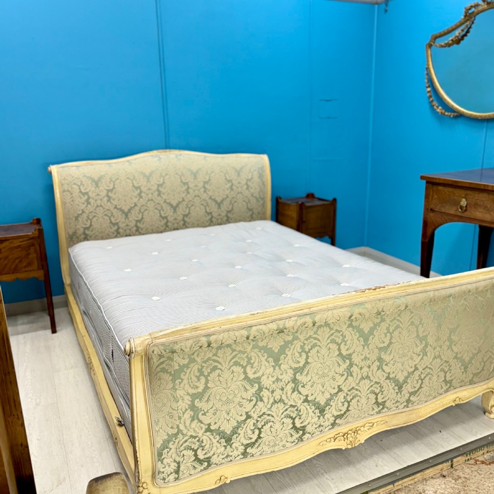 A king-size French bed frame featuring a carved cream-painted timber frame upholstered in green damask fabric with a scroll-end footboard. View II