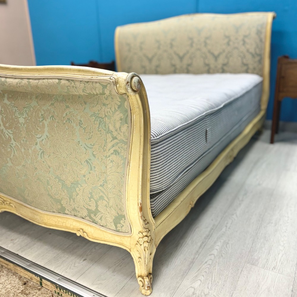 A king-size French bed frame featuring a carved cream-painted timber frame upholstered in green damask fabric with a scroll-end footboard. View III