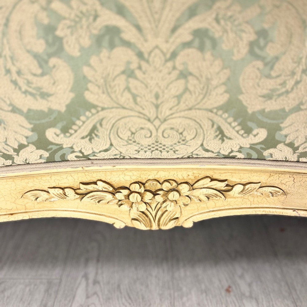 A king-size French bed frame featuring a carved cream-painted timber frame upholstered in green damask fabric with a scroll-end footboard. View V