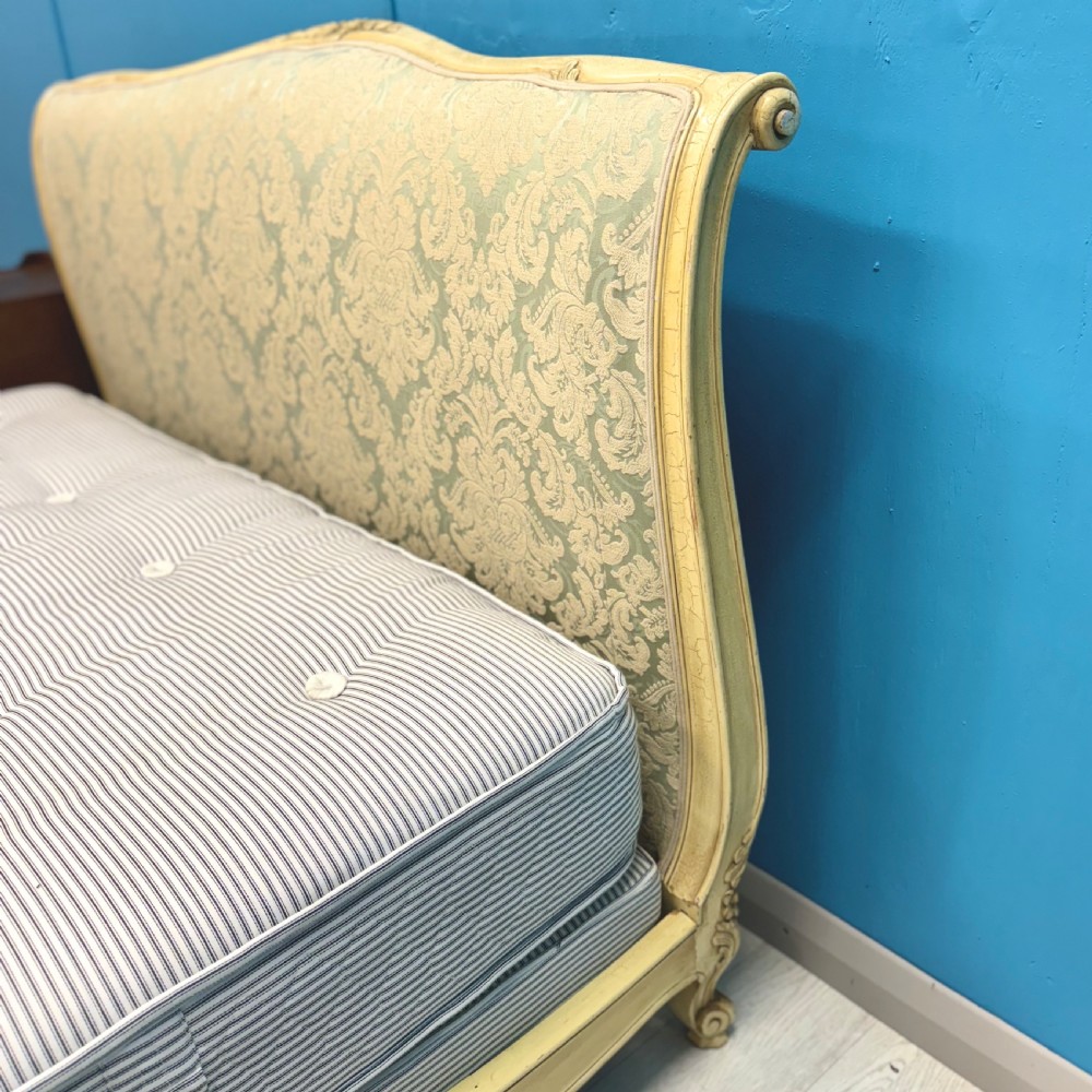 A king-size French bed frame featuring a carved cream-painted timber frame upholstered in green damask fabric with a scroll-end footboard. View IX