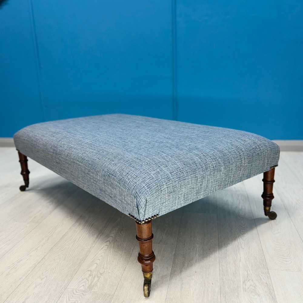 Large newly upholstered footstool on Regency legs with castors 