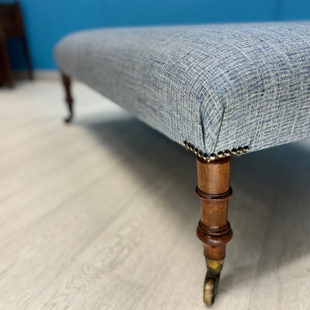 Large newly upholstered footstool on Regency legs with castors  View II