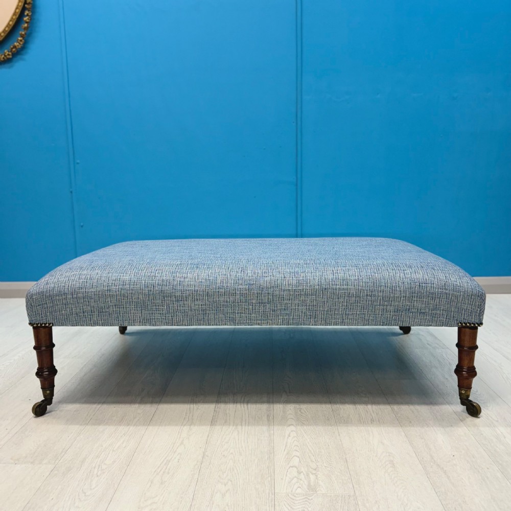 Large newly upholstered footstool on Regency legs with castors  View III