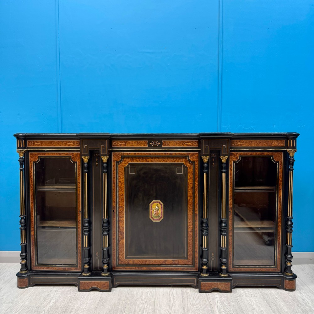 A Victorian ebonised credenza featuring a central inlaid panel door flanked by two glazed display compartments with brass mounts and fluted column details. View IV
