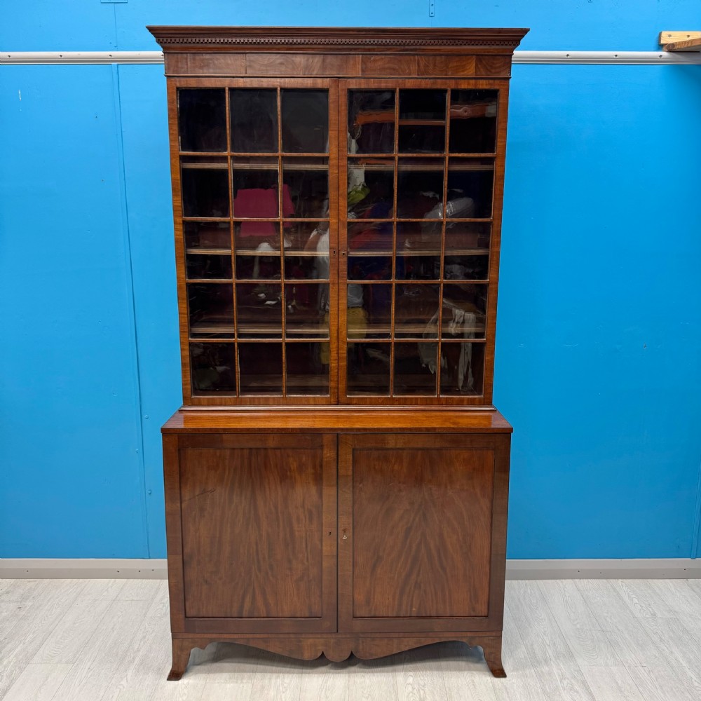 An antique Regency flame mahogany two-part bookcase featuring a glazed upper section with astragal bars and a double cupboard base. View II