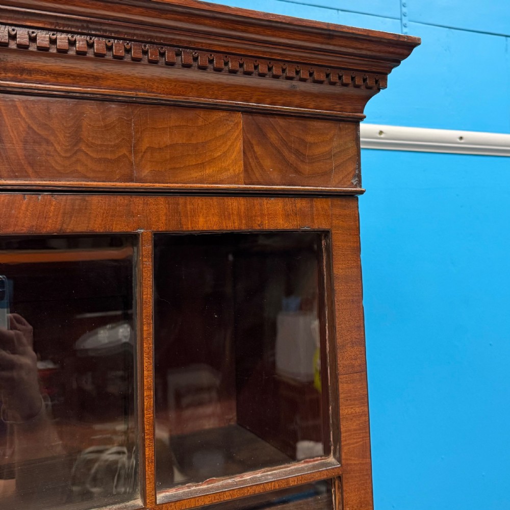 An antique Regency flame mahogany two-part bookcase featuring a glazed upper section with astragal bars and a double cupboard base. View VI