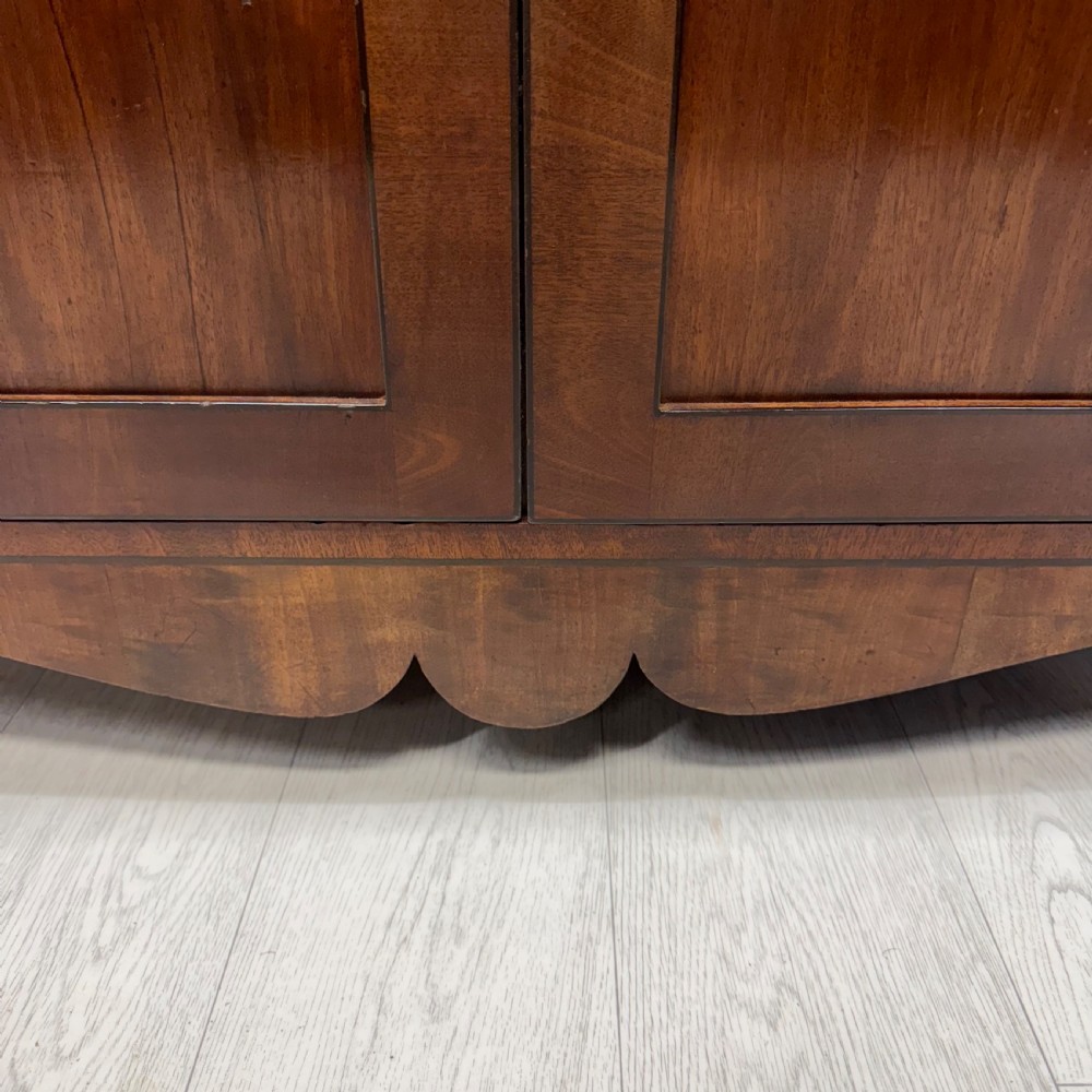 An antique Regency flame mahogany two-part bookcase featuring a glazed upper section with astragal bars and a double cupboard base. View X