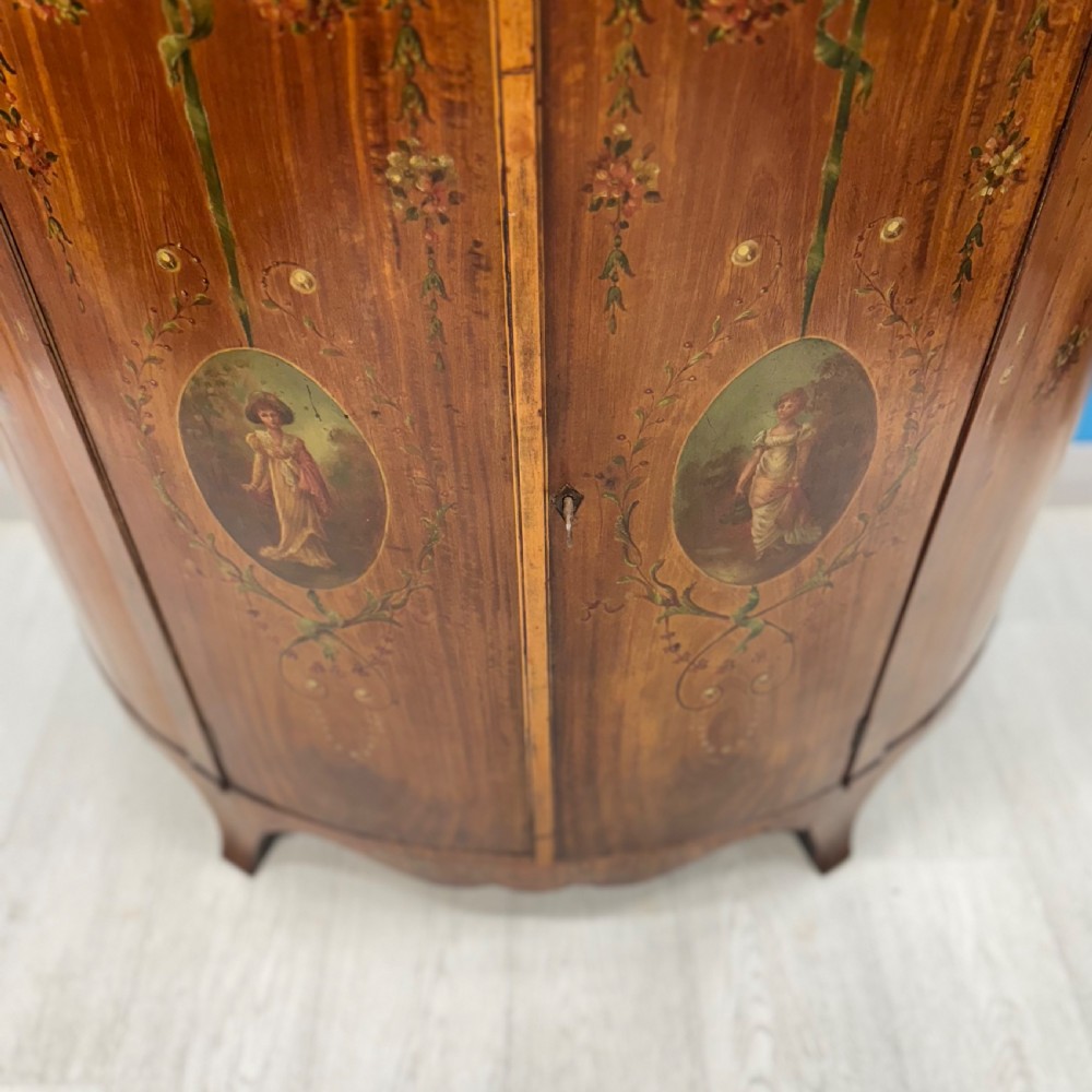 A 19th-century demi-lune satinwood side cabinet featuring hand-painted floral swags, ribbon motifs, and portrait medallions across its curved front doors. View VIII