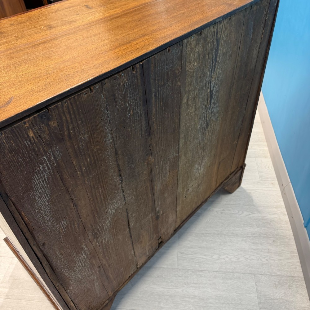 A Georgian oak chest of drawers featuring two short drawers over three long drawers with oval brass drop handles and bracket feet. View XII