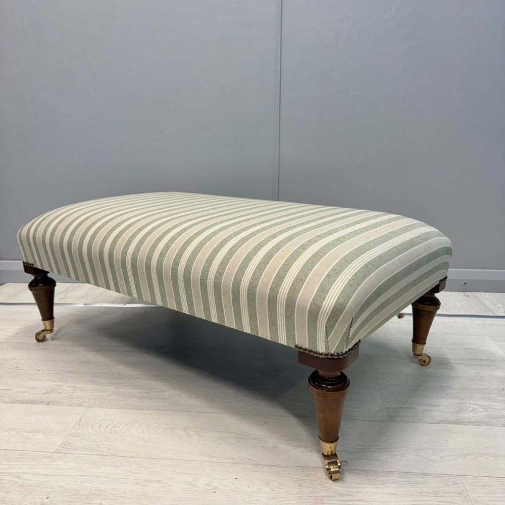 Upholstered French footstool on brass castors