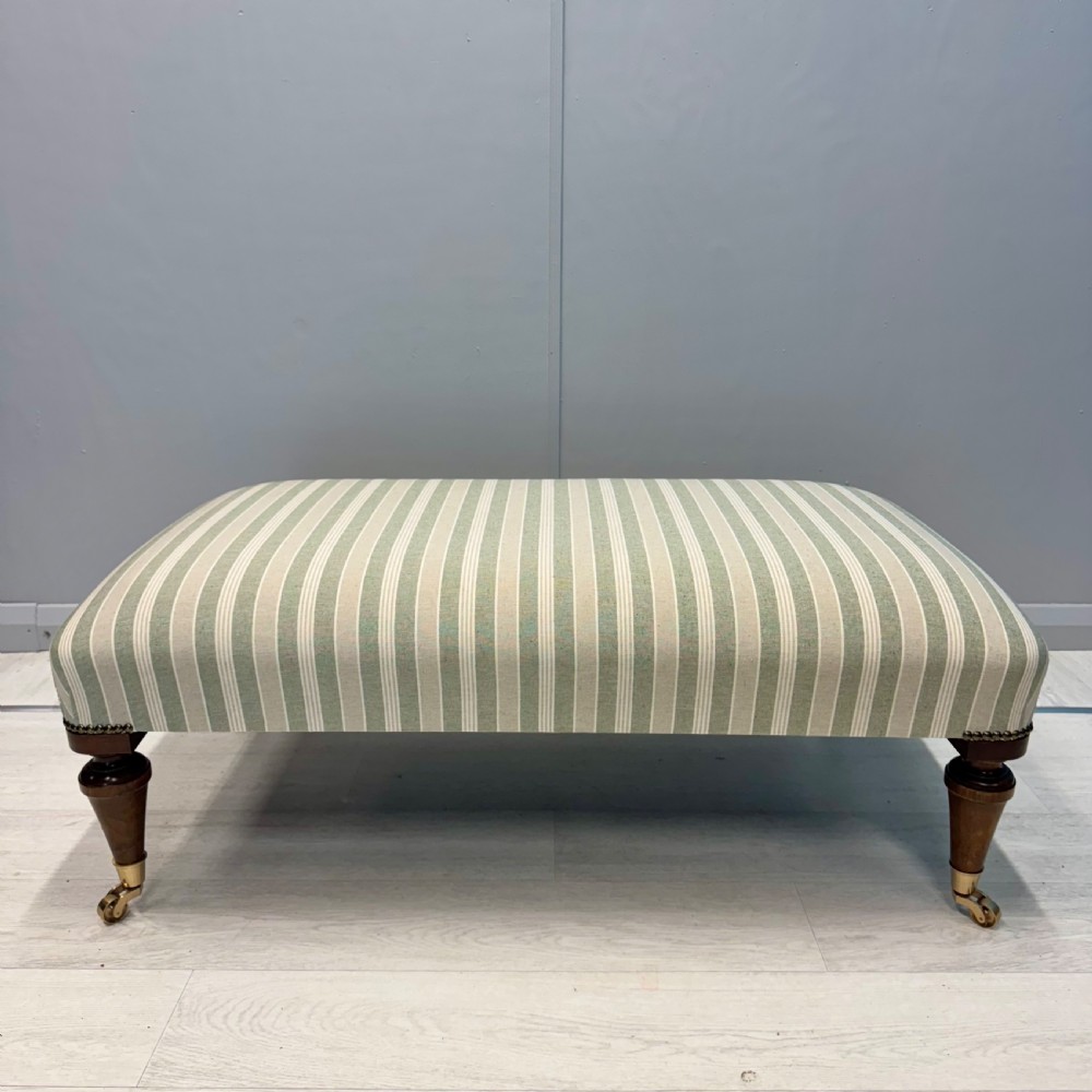 Upholstered French footstool on brass castors View II