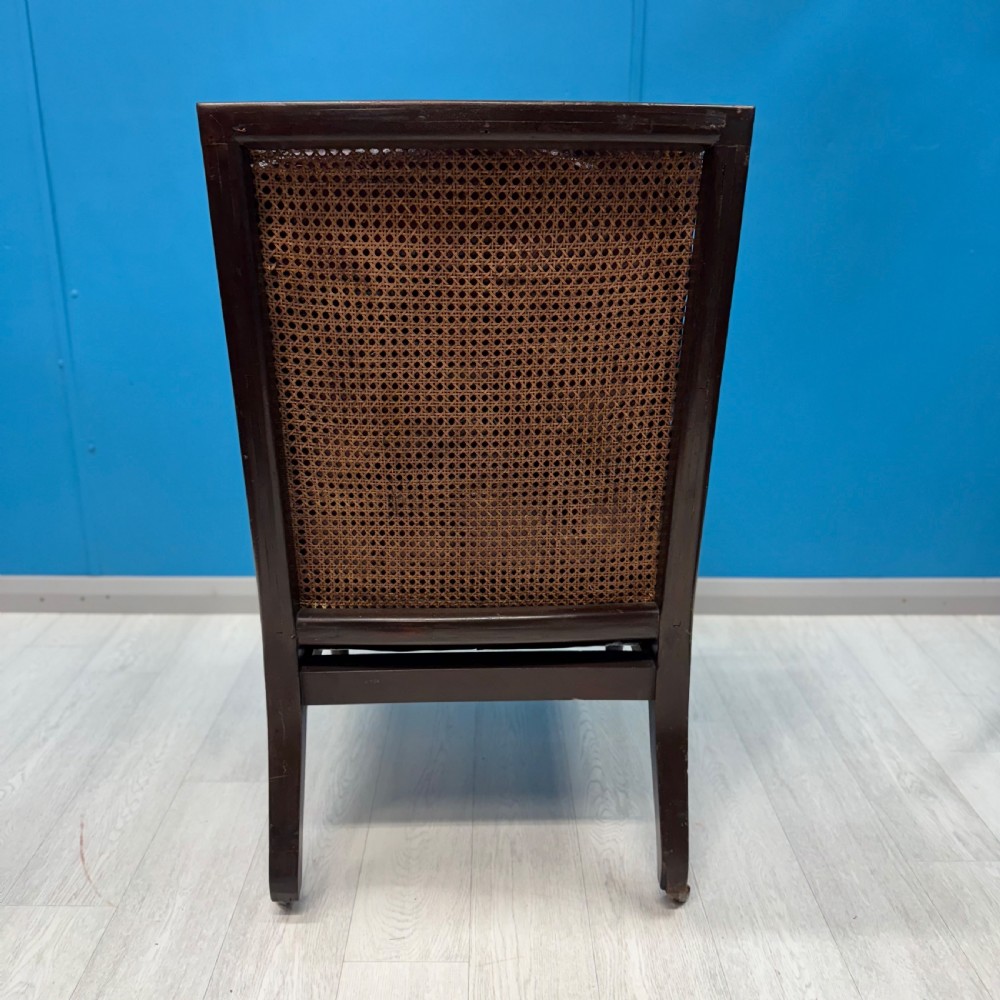 An early 19th-century mahogany bergere armchair with button-tufted burgundy leather cushions, woven cane side panels, turned front legs, and brass castors. View VIII