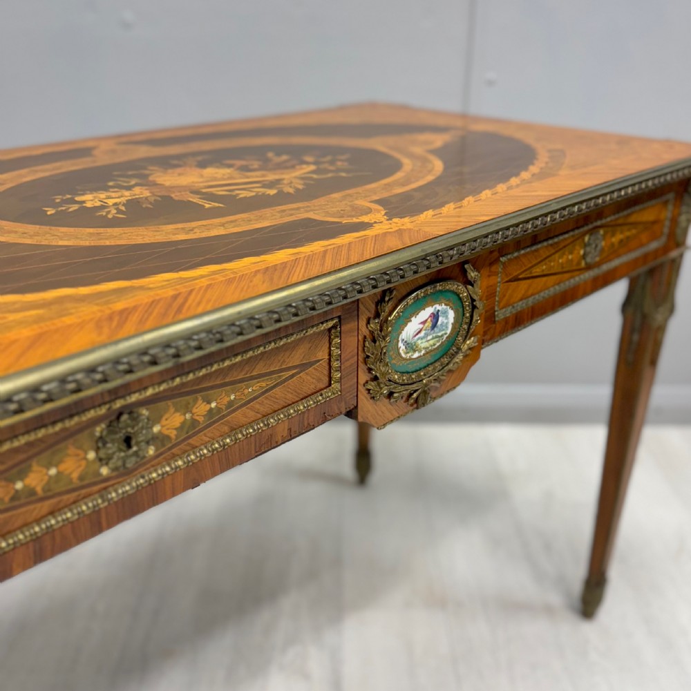 A French Louis XVI style kingwood centre table featuring intricate floral marquetry, brass mounts, a central porcelain plaque, and tapered square legs. View III