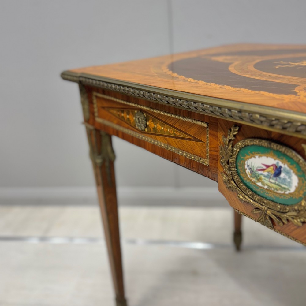 A French Louis XVI style kingwood centre table featuring intricate floral marquetry, brass mounts, a central porcelain plaque, and tapered square legs. View VII