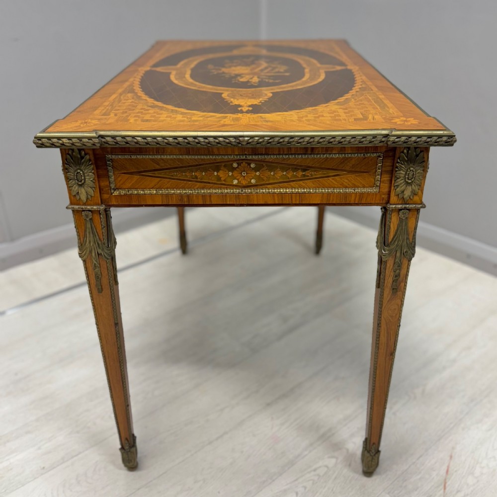 A French Louis XVI style kingwood centre table featuring intricate floral marquetry, brass mounts, a central porcelain plaque, and tapered square legs. View X