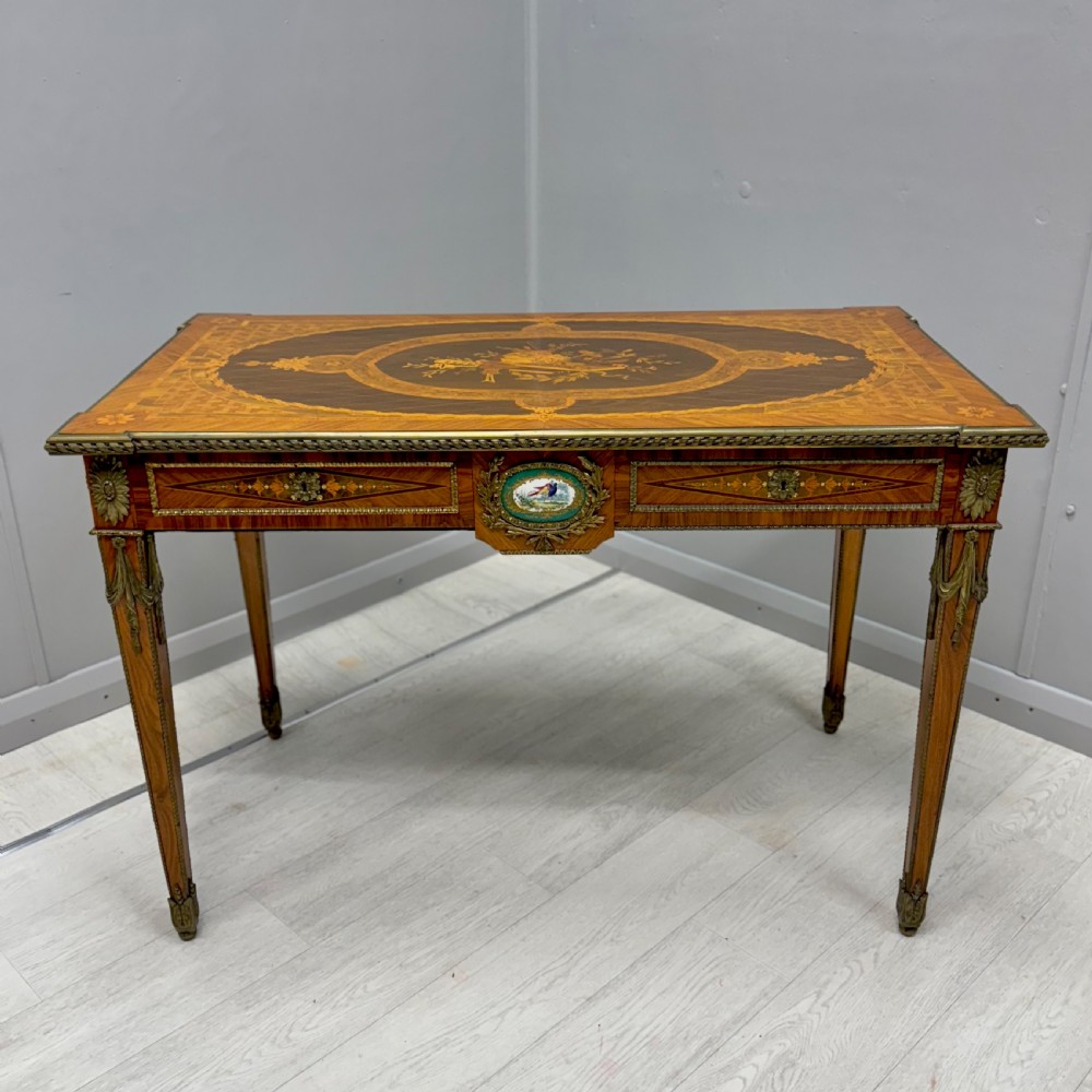 A French Louis XVI style kingwood centre table featuring intricate floral marquetry, brass mounts, a central porcelain plaque, and tapered square legs. View XI