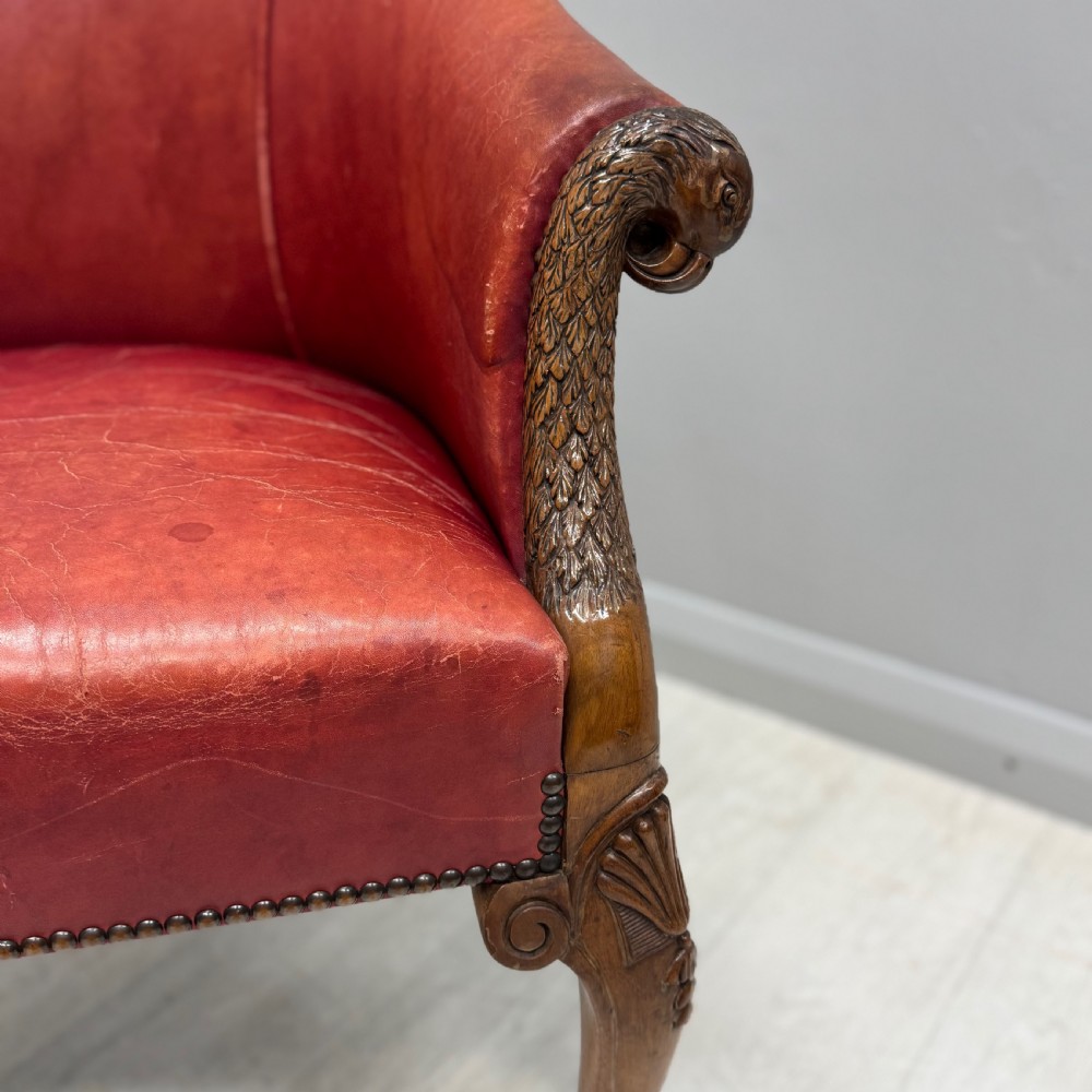 A red leather tub back armchair featuring carved mahogany cabriole legs, eagle head armrests, and brass studded trim. View III
