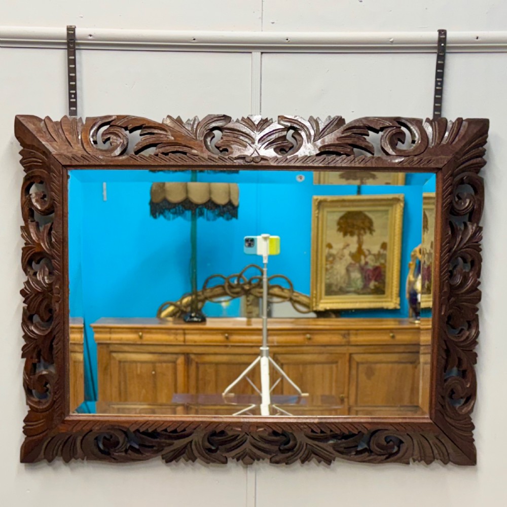 A rectangular 19th-century French wall mirror featuring a hand-carved dark oak frame decorated with openwork scrollwork and foliage motifs.