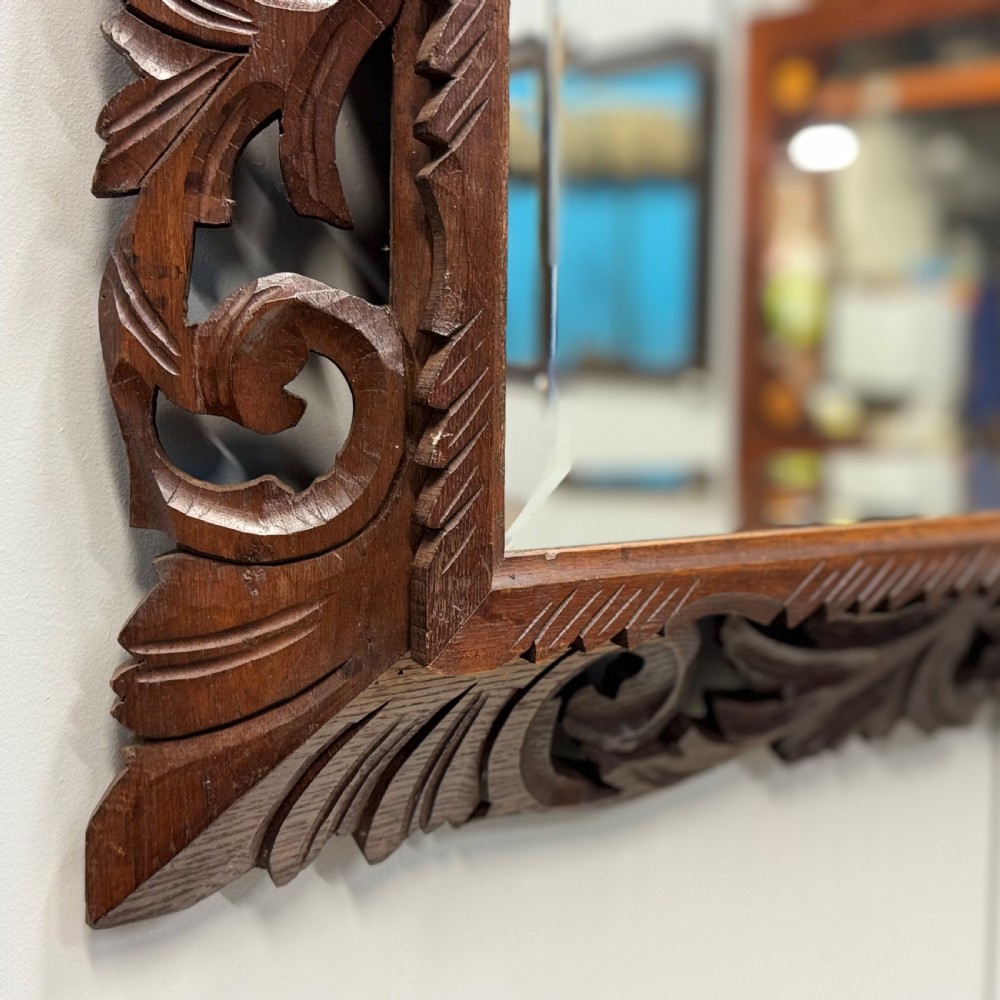 A rectangular 19th-century French wall mirror featuring a hand-carved dark oak frame decorated with openwork scrollwork and foliage motifs. View II