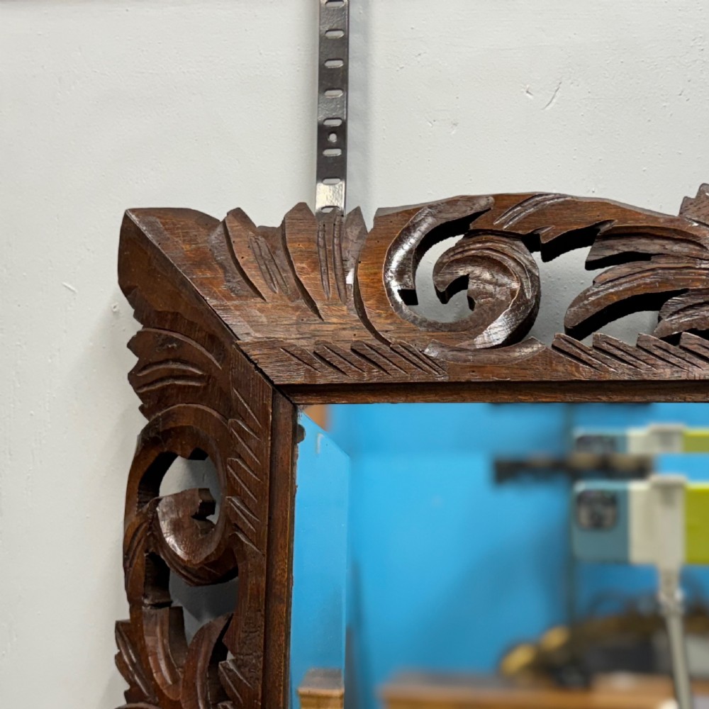 A rectangular 19th-century French wall mirror featuring a hand-carved dark oak frame decorated with openwork scrollwork and foliage motifs. View III