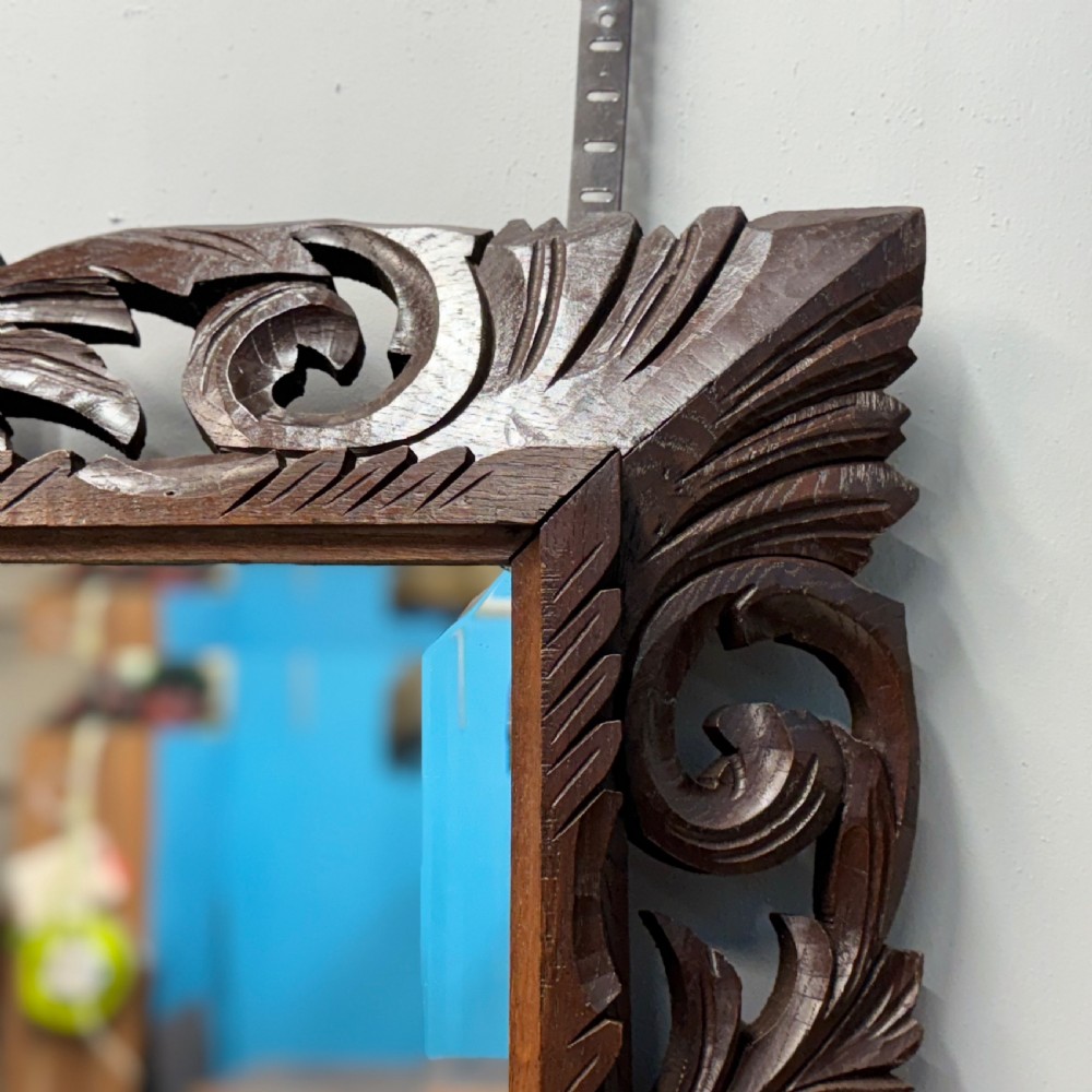 A rectangular 19th-century French wall mirror featuring a hand-carved dark oak frame decorated with openwork scrollwork and foliage motifs. View V