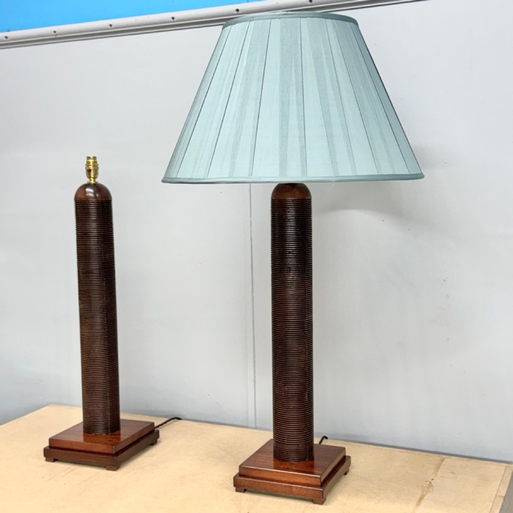 A matching pair of tall, dark wood table lamp bases featuring reeded cylindrical columns set on square plinths with brass bulb holders. View II