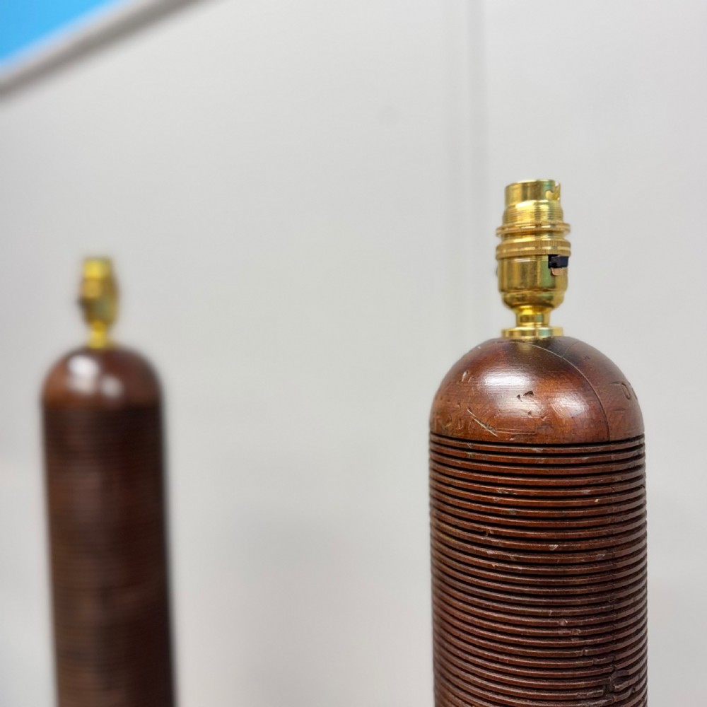 A matching pair of tall, dark wood table lamp bases featuring reeded cylindrical columns set on square plinths with brass bulb holders. View V