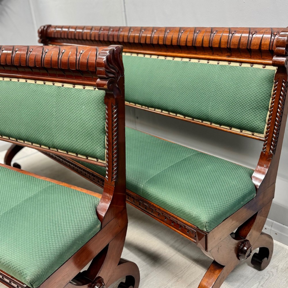 A pair of 19th-century carved mahogany benches featuring green upholstered seats and backrests supported by scrolled legs. View V