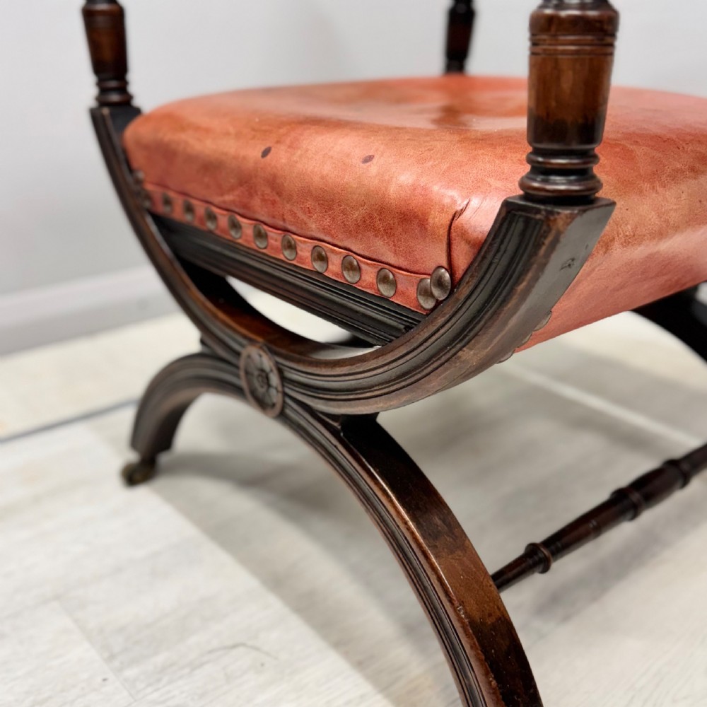 A French walnut X-frame armchair upholstered in tan leather with brass stud trim and carved wood accents. View III
