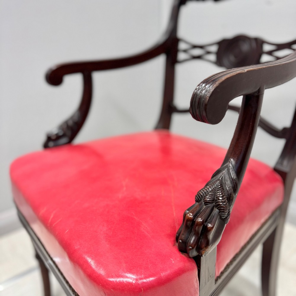 A set of four dark mahogany Regency style elbow chairs featuring carved rosettes, reeded arms, and red leather seats. View III