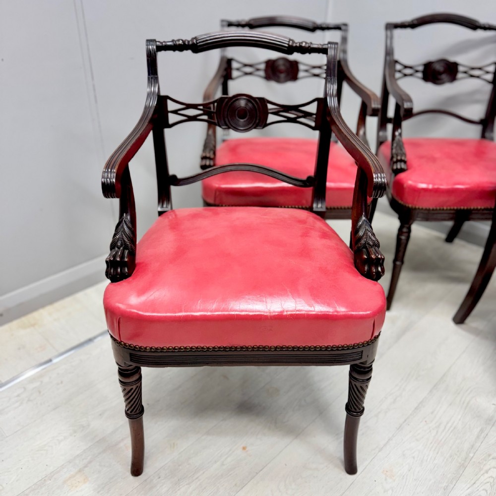 A set of four dark mahogany Regency style elbow chairs featuring carved rosettes, reeded arms, and red leather seats. View VI
