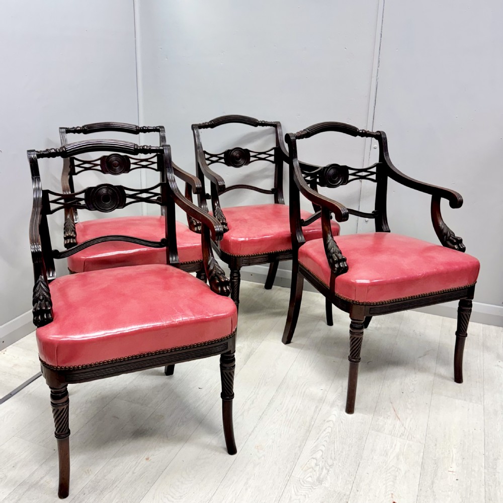 A set of four dark mahogany Regency style elbow chairs featuring carved rosettes, reeded arms, and red leather seats. View VII