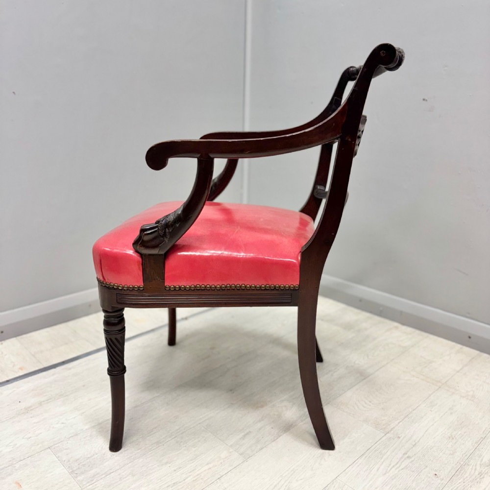 A set of four dark mahogany Regency style elbow chairs featuring carved rosettes, reeded arms, and red leather seats. View IX
