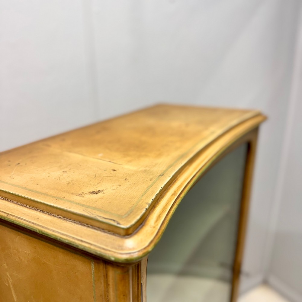 A freestanding cream painted bookcase featuring a single curved glass door, floral painted motifs, cabriole legs, and a sage green interior with adjustable shelves. View V