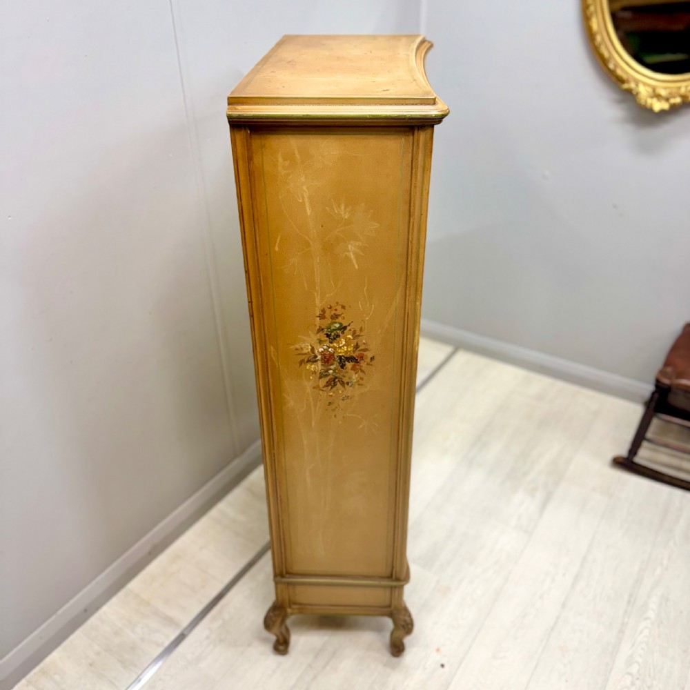 A freestanding cream painted bookcase featuring a single curved glass door, floral painted motifs, cabriole legs, and a sage green interior with adjustable shelves. View VIII