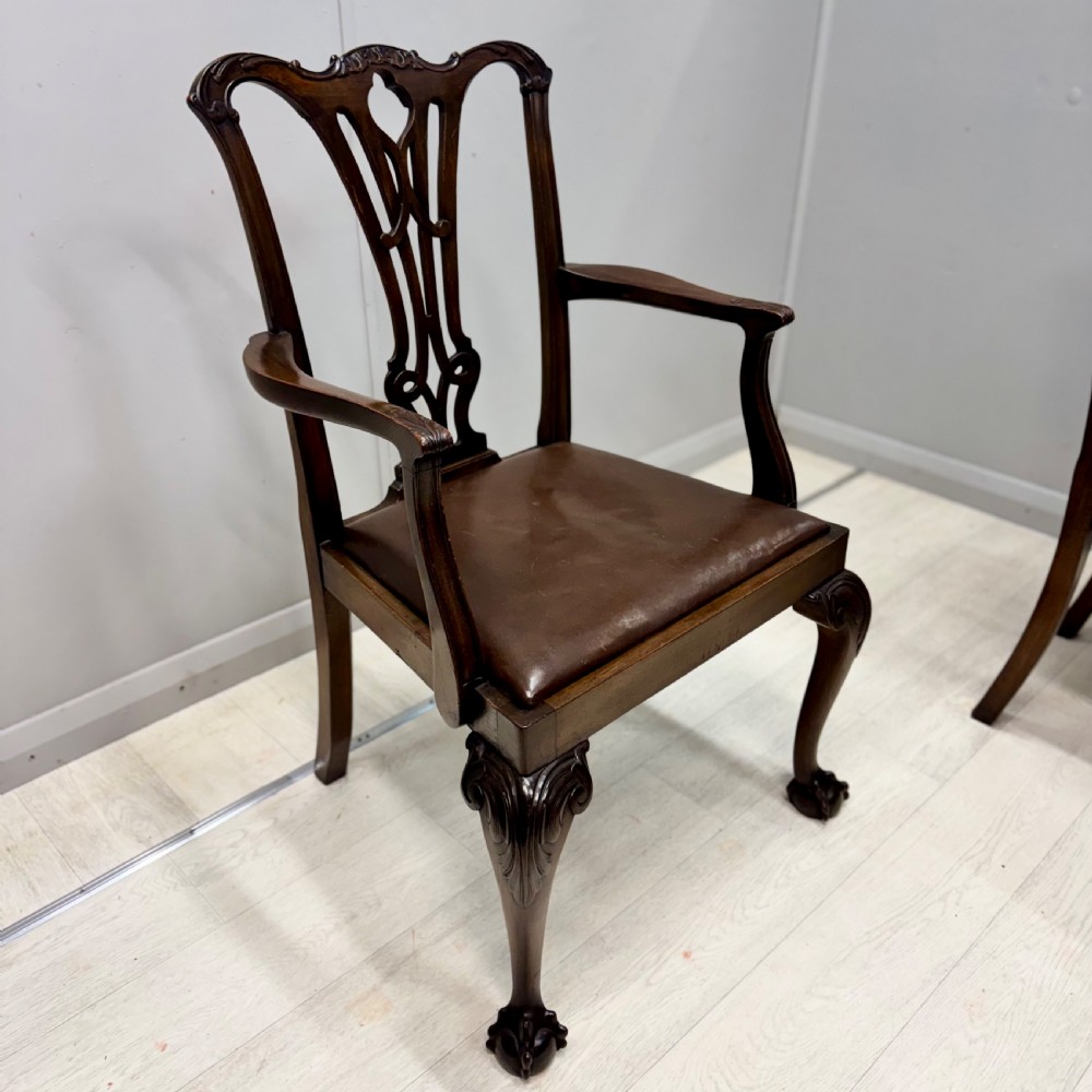 A set of eight Georgian style mahogany dining chairs featuring pierced back splats, brown leather seats, and cabriole legs ending in ball and claw feet. View V
