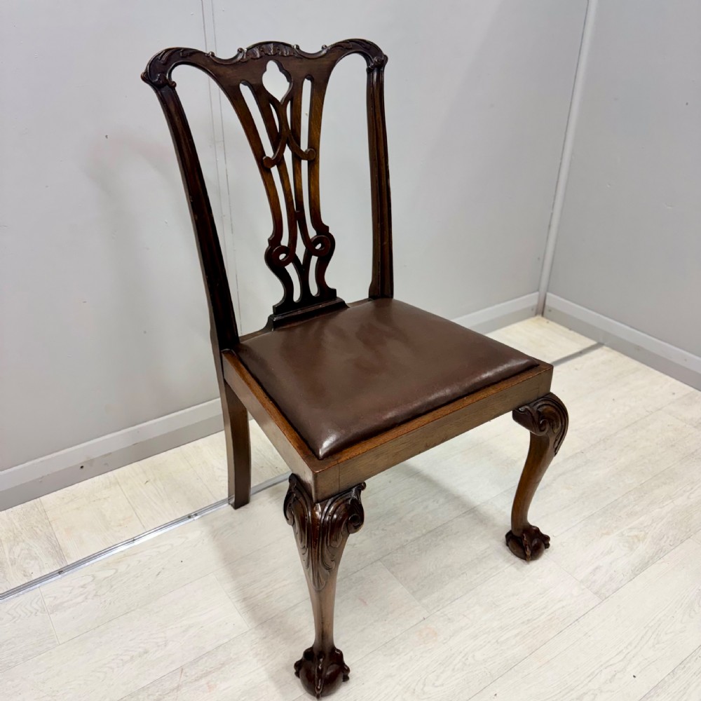 A set of eight Georgian style mahogany dining chairs featuring pierced back splats, brown leather seats, and cabriole legs ending in ball and claw feet. View VII