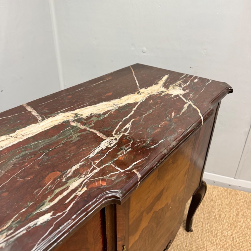 An early nineteenth-century French style marquetry commode cabinet with a marble top, cabriole legs, central inlaid architectural landscape scene, and decorative brass mounts. View VI