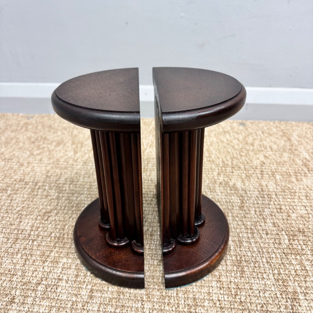 A pair of dark mahogany semi-circular bookends shaped like classical fluted columns.