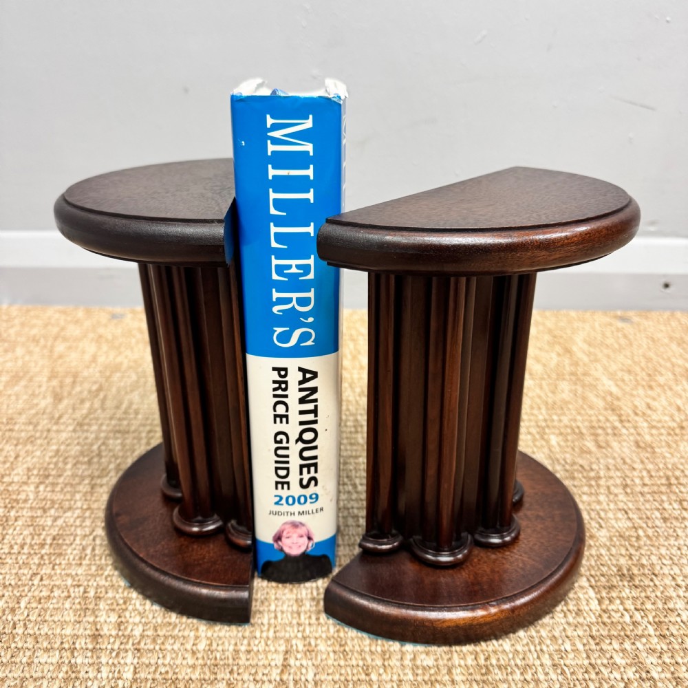 A pair of dark mahogany semi-circular bookends shaped like classical fluted columns. View X