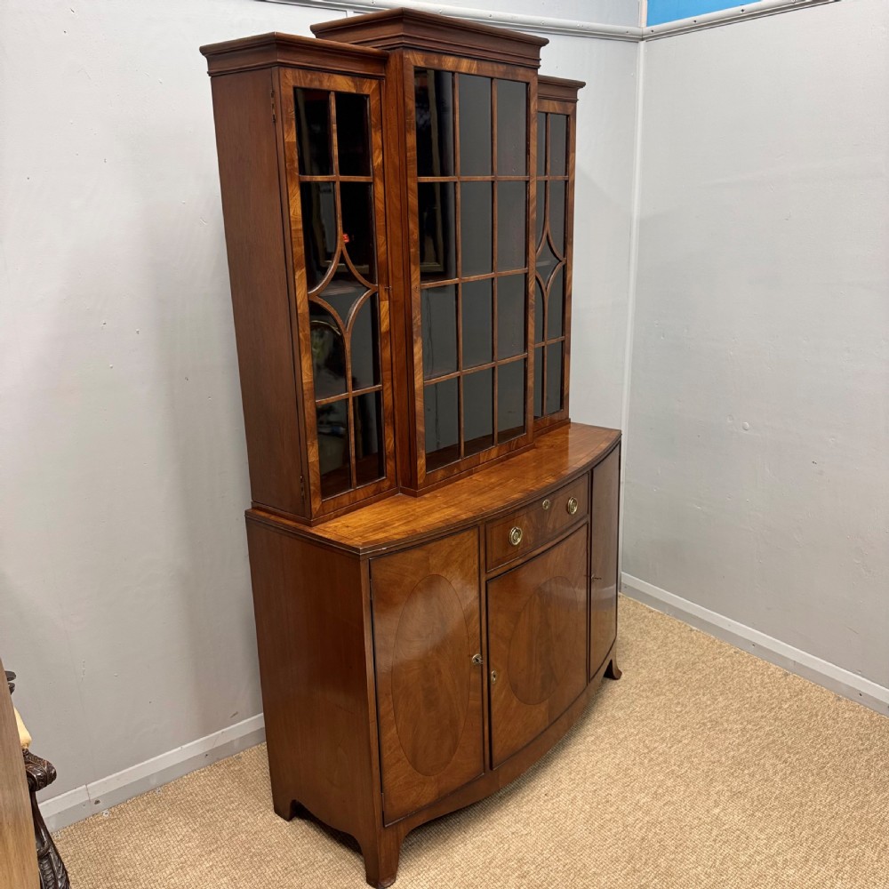 A mahogany bow front glazed bookcase cabinet featuring geometric astragal glazing bars above a cupboard base with flame veneer panels. View II