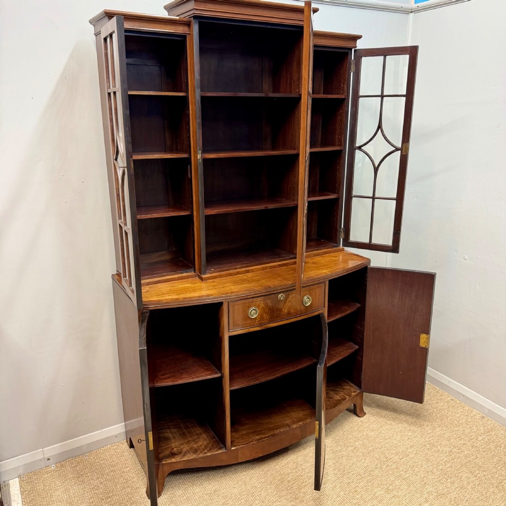 A mahogany bow front glazed bookcase cabinet featuring geometric astragal glazing bars above a cupboard base with flame veneer panels. View III