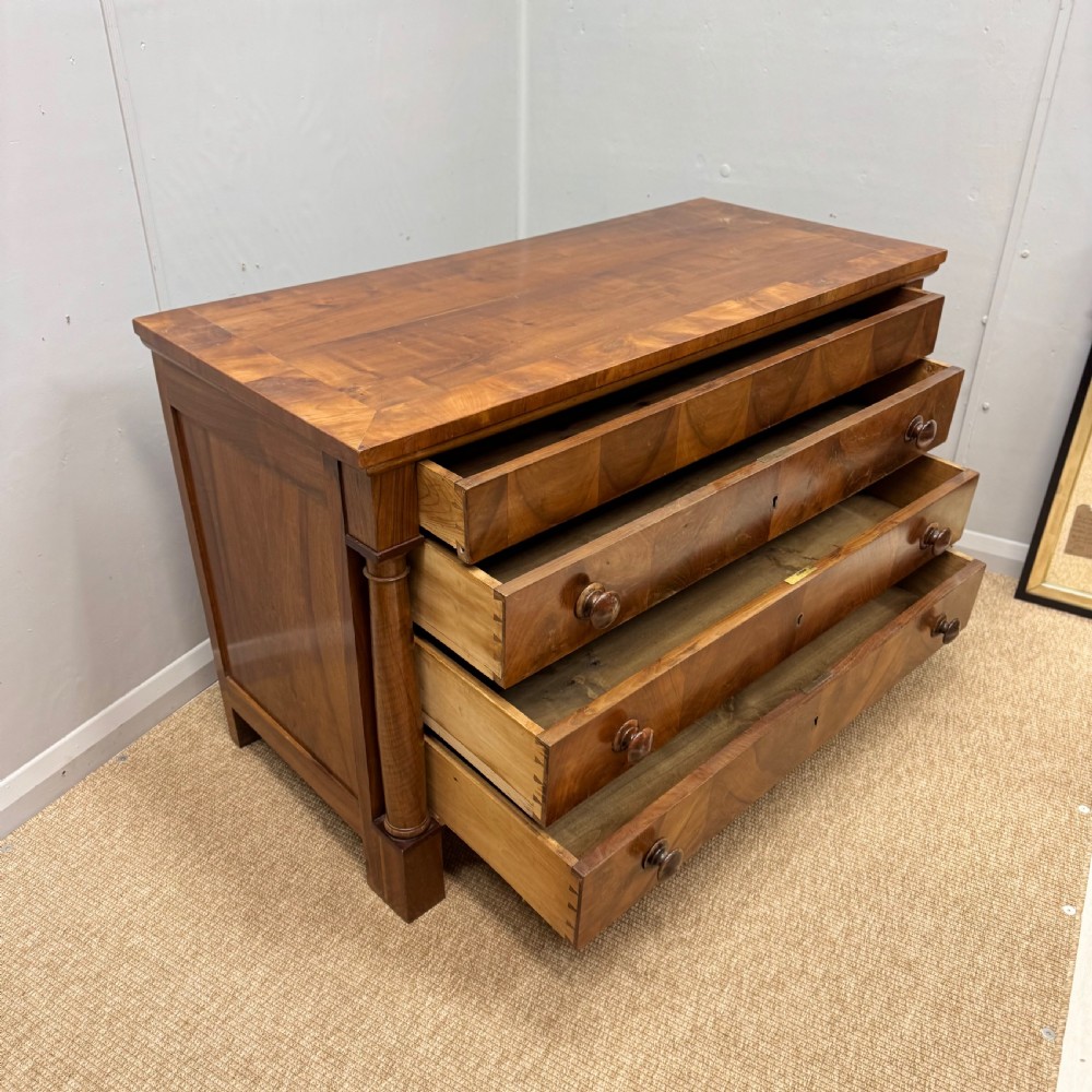 A 19th-century French cherry wood commode featuring three lower drawers with turned knobs, a top frieze drawer, and side columns on block feet. View III