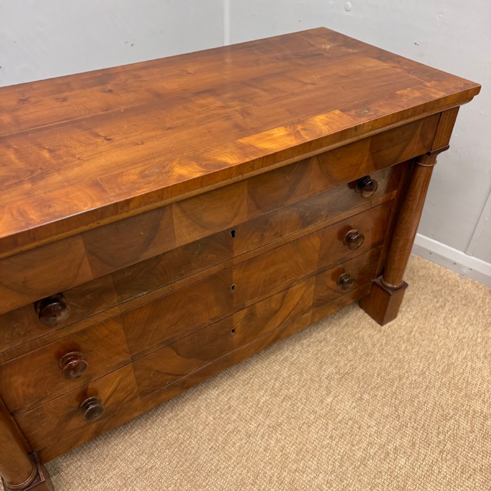 A 19th-century French cherry wood commode featuring three lower drawers with turned knobs, a top frieze drawer, and side columns on block feet. View IV