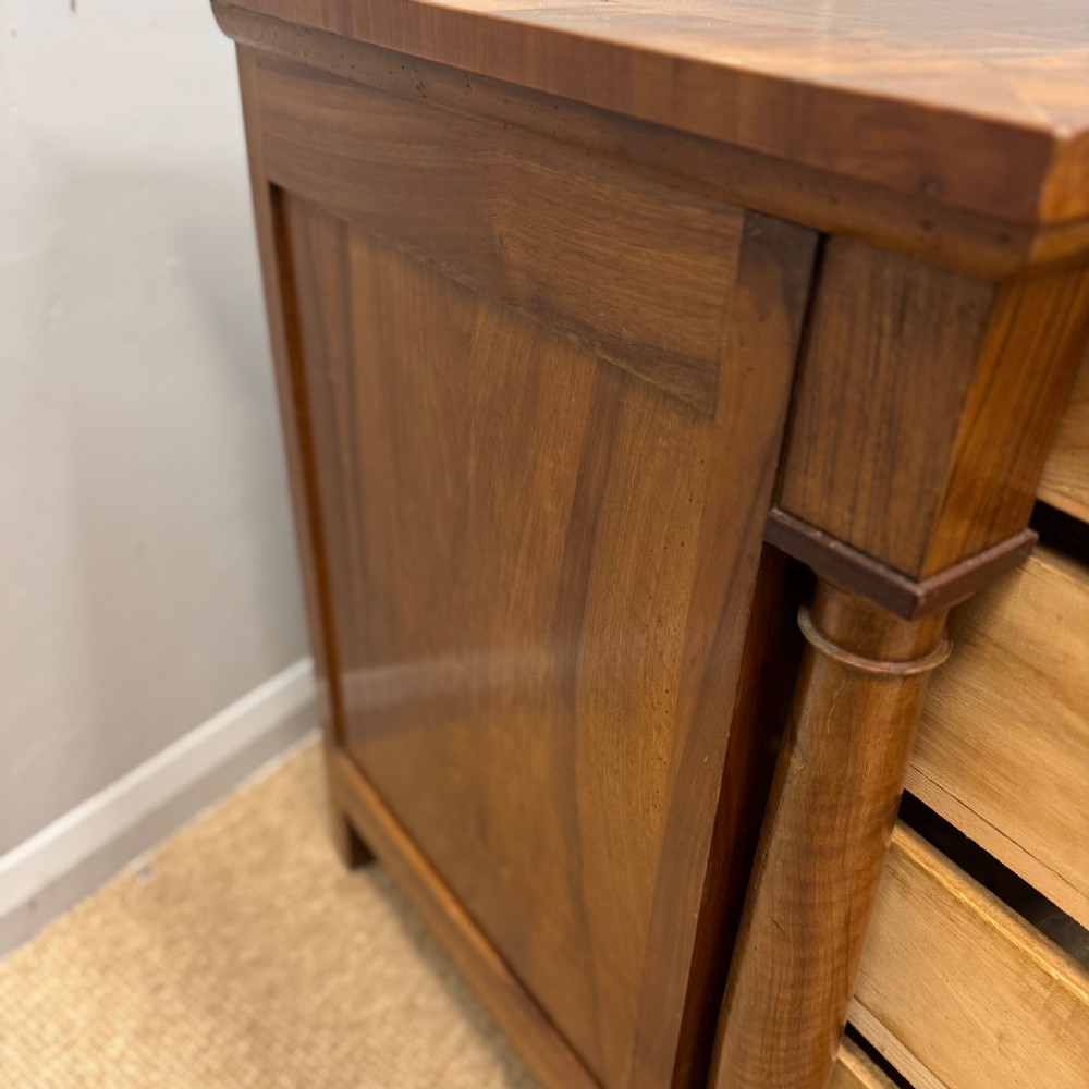 A 19th-century French cherry wood commode featuring three lower drawers with turned knobs, a top frieze drawer, and side columns on block feet. View V