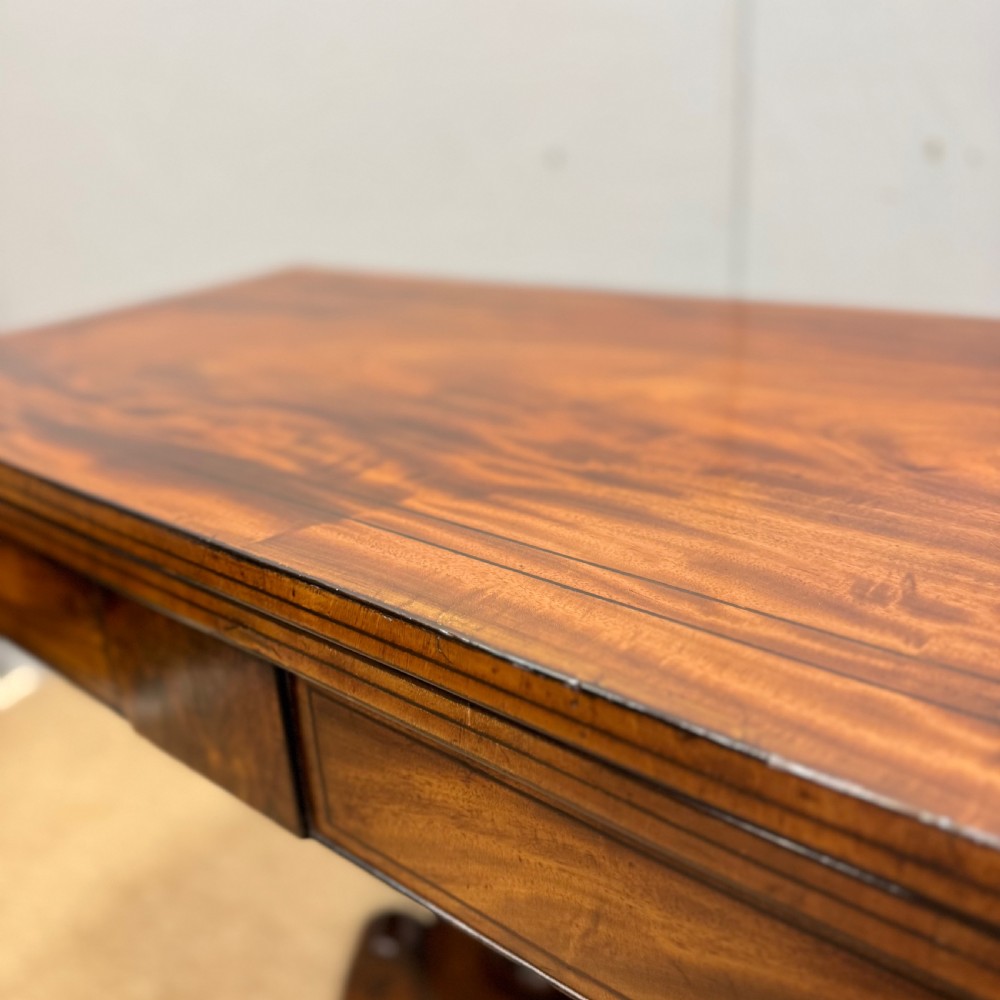 A Georgian satinwood games table featuring ebony line inlay, a turned central pedestal, and four splayed legs with brass paw feet. View II